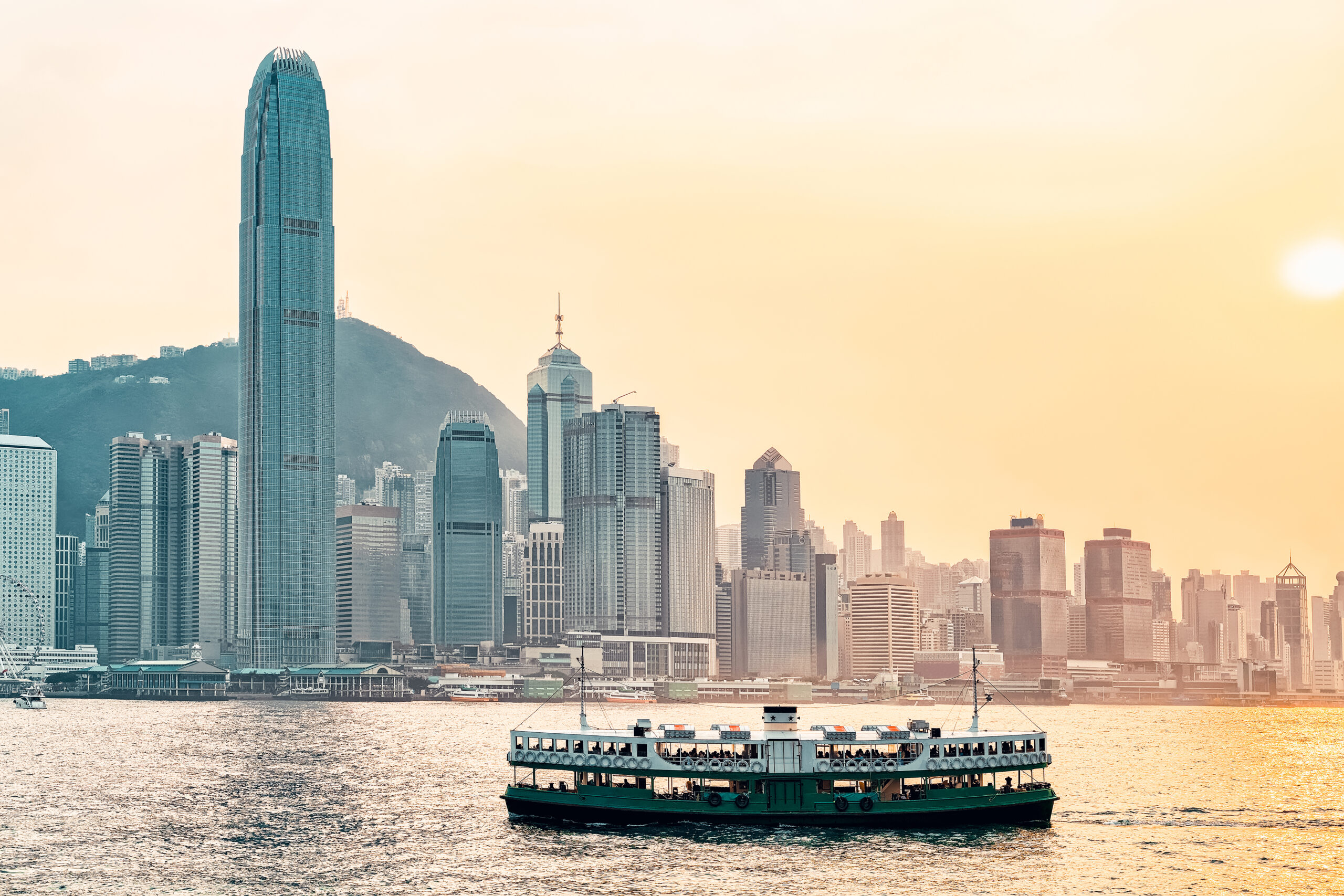Star ferry at Victoria Harbor and Hong Kong skyline at sundown. View from Kowloon on HK Island.
