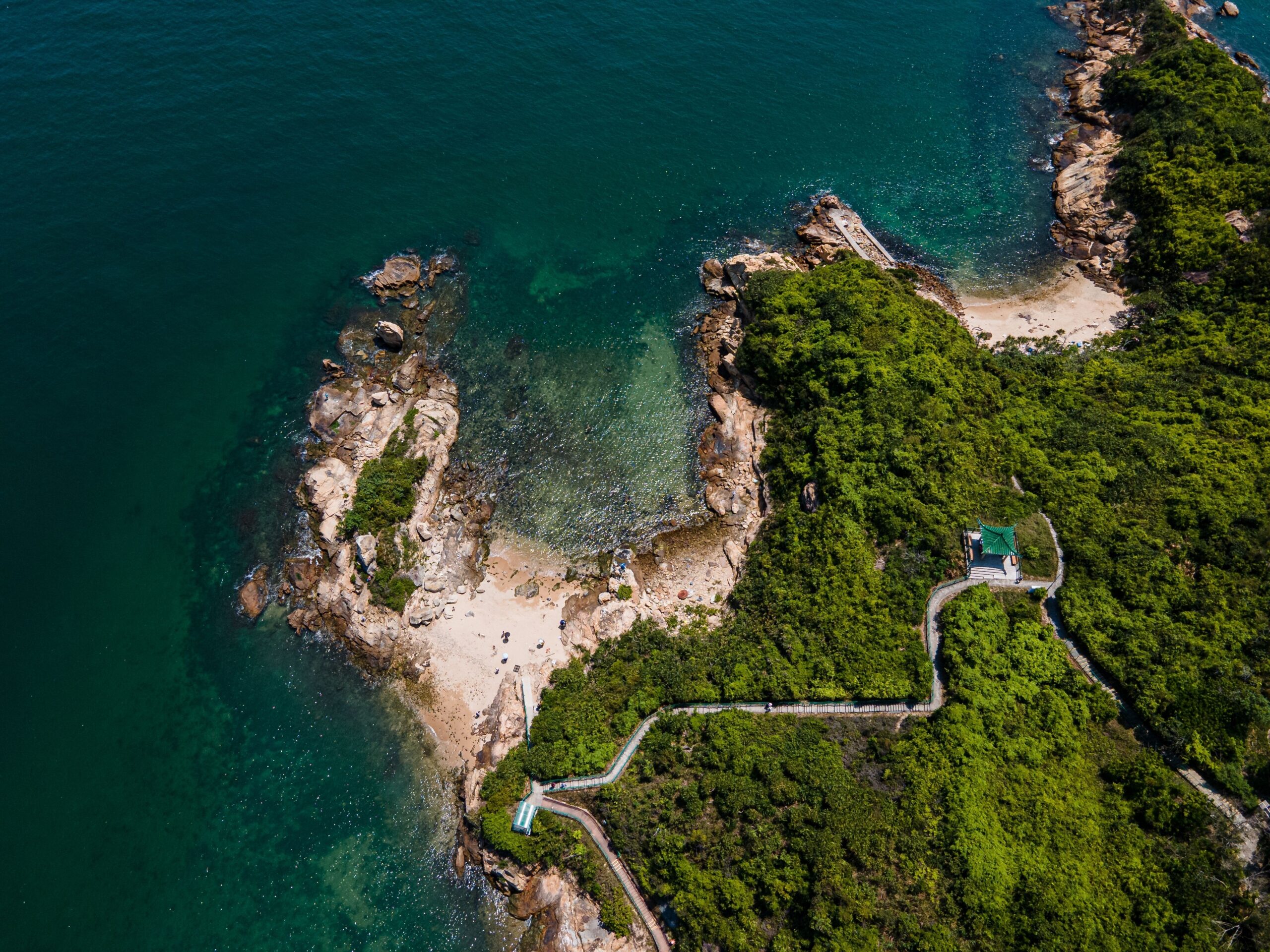 An aerial shot of a Peng Chau beach surrounded by green trees in Hong Kong